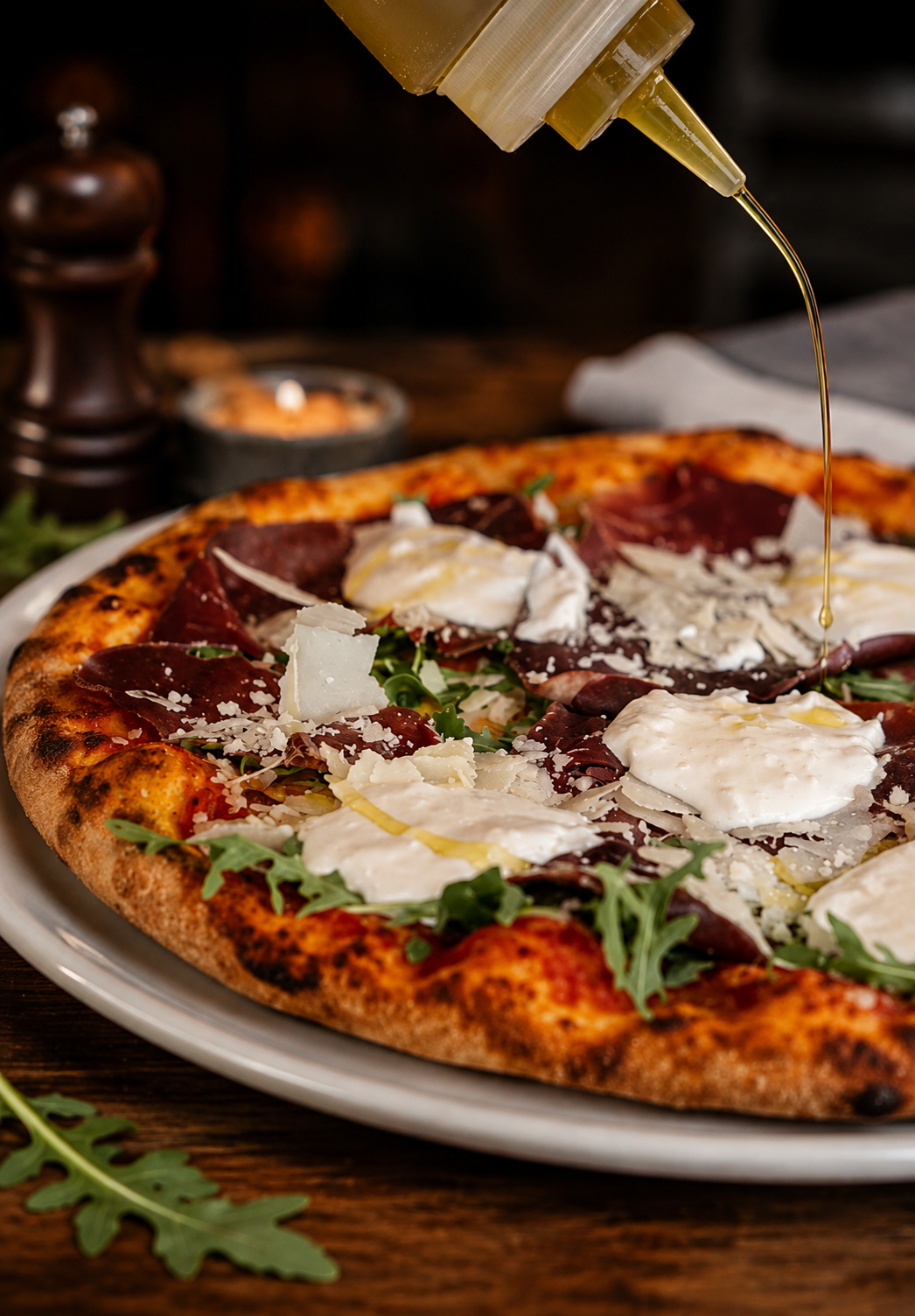 Pizza bresaola, burrata et roquette arrosée d'huile d'olive au restaurant L'Aquarama