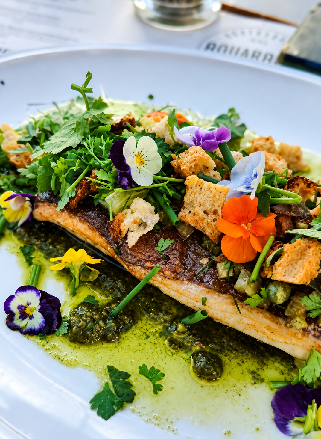 Filet d'omble poêlé, herbes fraîches et fleurs comestibles, servi en terrasse